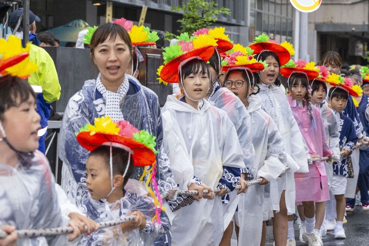 レインウェアで雨対策をして山車行列に参加する子どもたち
