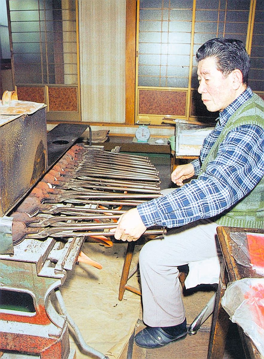 【写真説明】「私のせんべいのファンがいる限り頑張りたい」と話し、手焼き型を動かす大久保勝夫さん